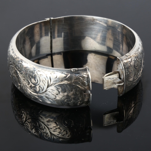 1295 - A mid-20th century silver hinged bangle, allover engraved foliate decoration, maker's marks S and E,... 