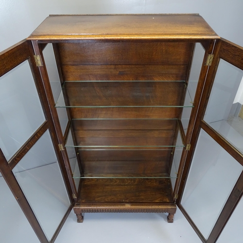 2511 - A 1930s oak two door display cabinet, with three glazed shelves and carved linenfold decoration. 79x... 