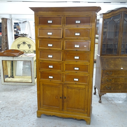 2618 - An early 20th century oak notaire, with 12 pigeon holes having rising lids, panelled cupboards under... 