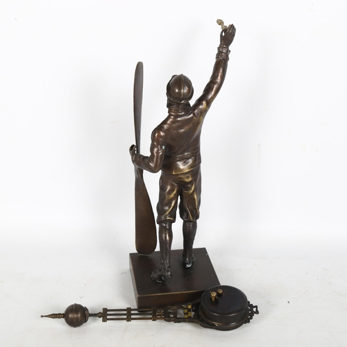 283 - A bronze figure of a pilot standing holding a plane propeller and a swing clock aloft in the second ... 