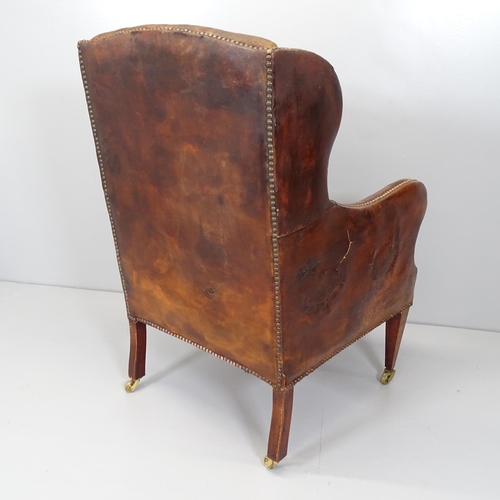 2654 - An Edwardian button back brown leather-upholstered wingback fireside arm chair.