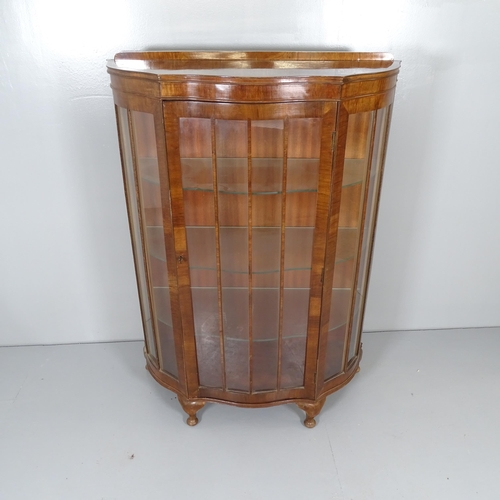 2675 - A 1930s mahogany display cabinet of serpentine form, with single glazed door, three fixed shelves an... 