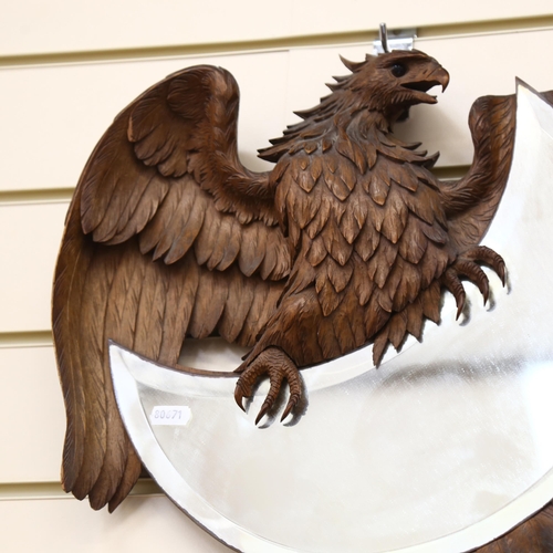 94 - A Black Forest crescent-shaped wall mirror, framed by a winged eagle, W38cm