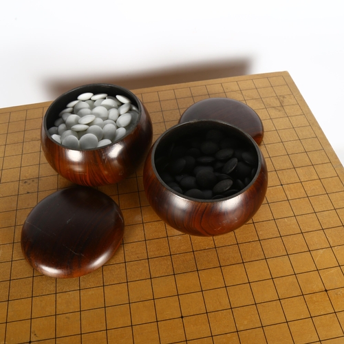 693 - A Japanese solid wood Go board with 2 pots of black and white counters, H28cm, L23cm, W46cm