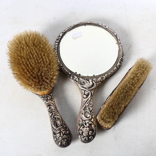 809 - An Art Nouveau silver-backed dressing table mirror and 2 brushes, with ornate scrolled and embossed ... 