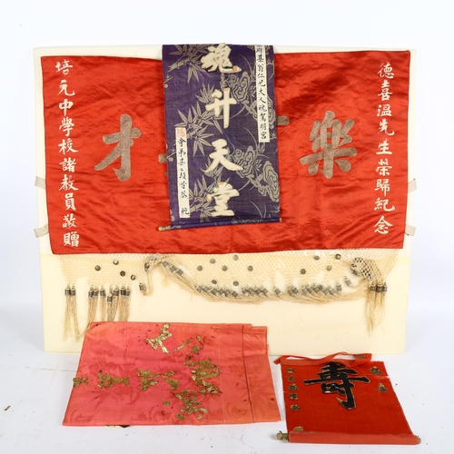 592 - A boxed Oriental red silk wall hanging, with embroidered script and fringe, 73cm across, and a box c... 