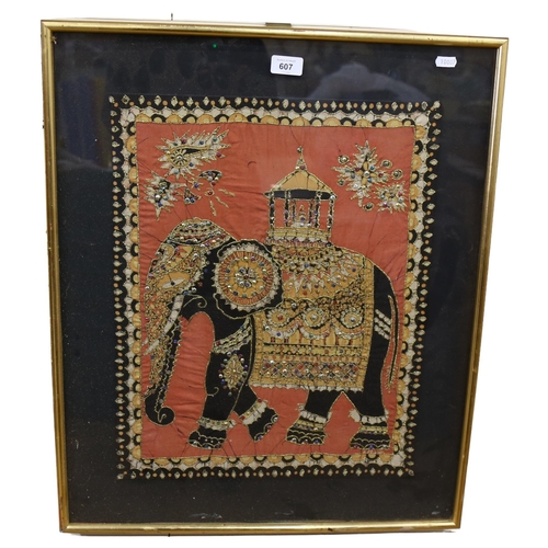 607 - A framed Eastern embroidered fabric panel, with gilded decoration depicting a caparisoned elephant, ... 