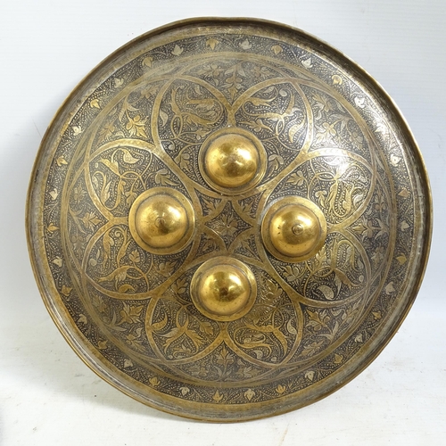 537 - A Cairo Ware Dhal convex shield with polished bosses, with allover engraved decoration, diameter 37c... 