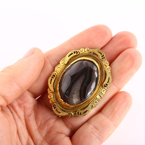 1131 - A Victorian Etruscan style banded agate brooch, unmarked yellow metal settings with wirework decorat... 