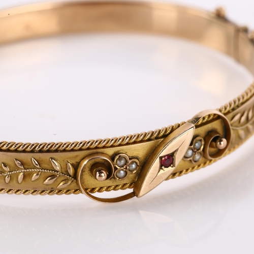 1158 - An Edwardian 9ct rose gold ruby and pearl hinged bangle, with floral motif and rope twist border, ma... 