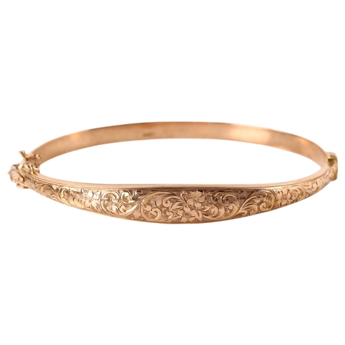 1167 - An early 20th century 9ct rose gold hinged bangle, engraved floral and foliate decoration, maker's m... 