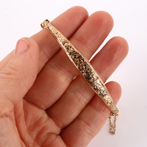 1167 - An early 20th century 9ct rose gold hinged bangle, engraved floral and foliate decoration, maker's m... 