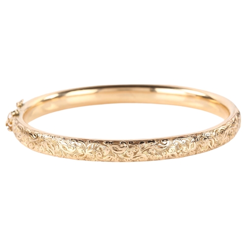 1200 - An early 20th century 9ct rose gold hinged bangle, engraved foliate decoration, band width 6.3mm, in... 