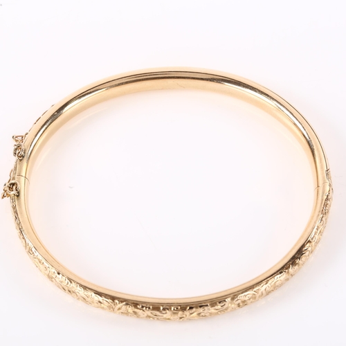 1200 - An early 20th century 9ct rose gold hinged bangle, engraved foliate decoration, band width 6.3mm, in... 