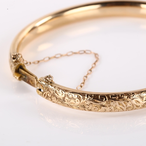 1200 - An early 20th century 9ct rose gold hinged bangle, engraved foliate decoration, band width 6.3mm, in... 