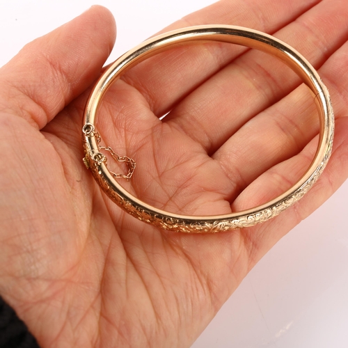 1200 - An early 20th century 9ct rose gold hinged bangle, engraved foliate decoration, band width 6.3mm, in... 