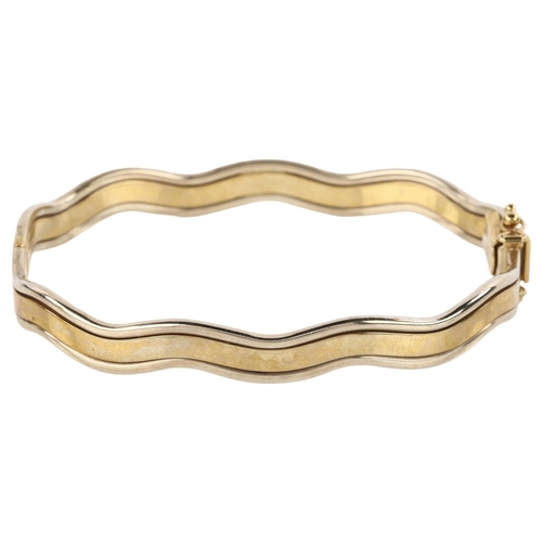 1206 - A 9ct two-tone gold hinged bangle, wave design, band width 7.7mm, internal circumference 18cm, 13.2g