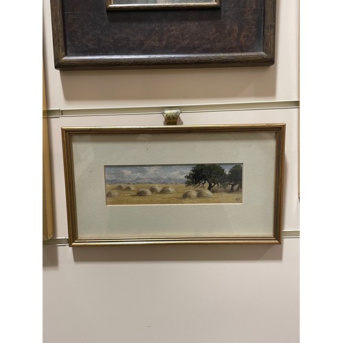 567 - Alfred East (1844 - 1913), haystacks, oil on board, signed with monogram, 6cm x 21cm, framed