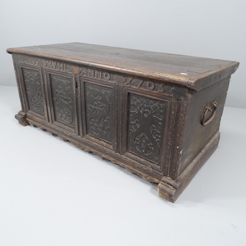 2028 - An 18th century panelled oak coffer with carved decoration. 132x55x64cm.