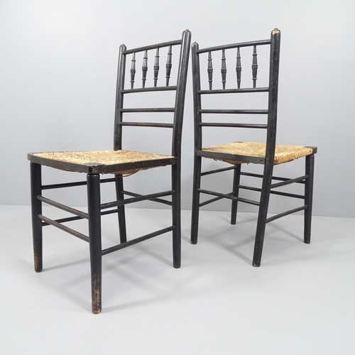 2040 - A pair of Morris & Company Arts & Crafts spindle back ebonised Sussex chairs with rush seats.