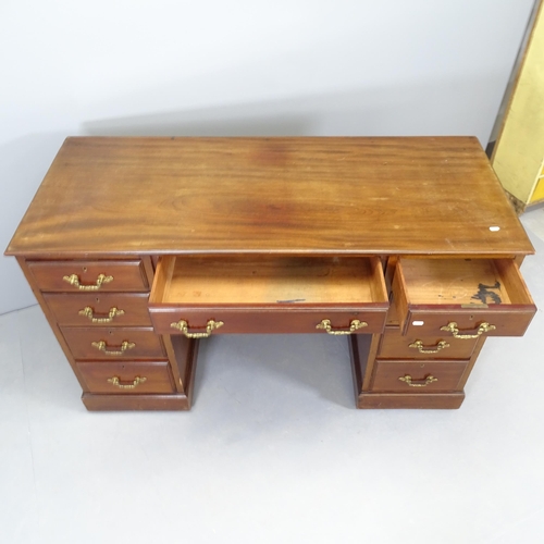 2570 - An antique mahogany kneehole writing desk, with nine drawers and raised on casters. 138x83x57cm. Kne... 