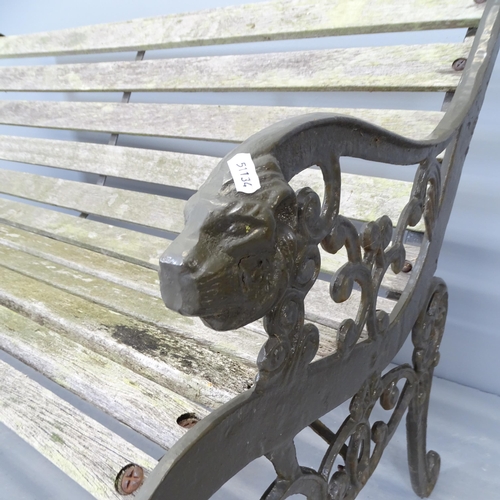 2667 - A teak slatted garden bench with cast iron ends, with lion decoration. 130x73x65cm.