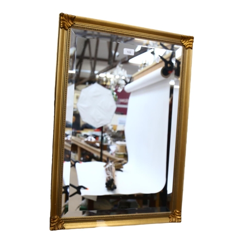 102 - A modern gilt-framed bevel-edge wall mirror, 73cm x 51cm