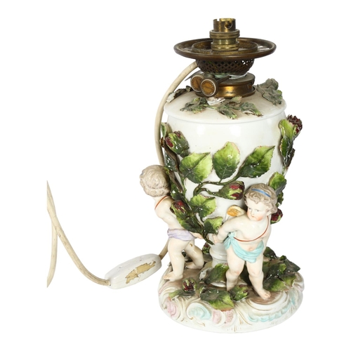 338 - A Continental porcelain oil lamp converted to electric, supported by cherub figures, H33cm