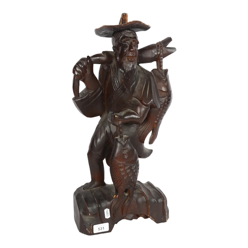 531 - South East Asian stained carved wood study of a fisherman, H52cm