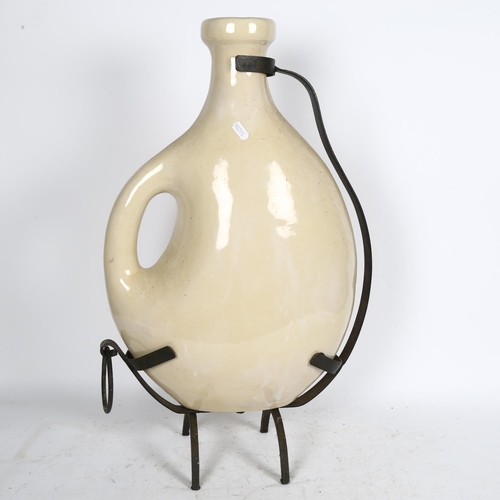 541 - A large ceramic wine jug in wrought-iron stand, H60cm