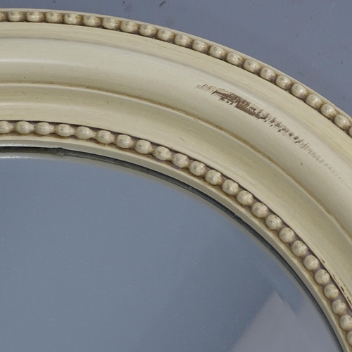 2236 - An Edwardian cream painted cushion framed oval wall mirror. 87x67cm