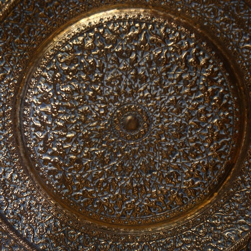 583 - Ornate Eastern hammered brass table-top with allover floral and foliate decoration, 61.5cm