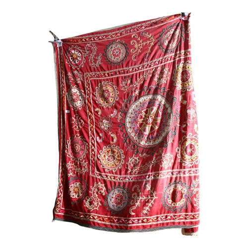 630 - A mid-20th century Uzbek Suzani with embroidered patterns on a red cloth base, 175cm x 160cm