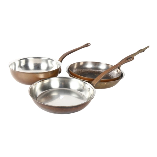 711 - A set of 3 polished copper pans with iron handles, largest 30cm diameter, and a copper pan with bras... 