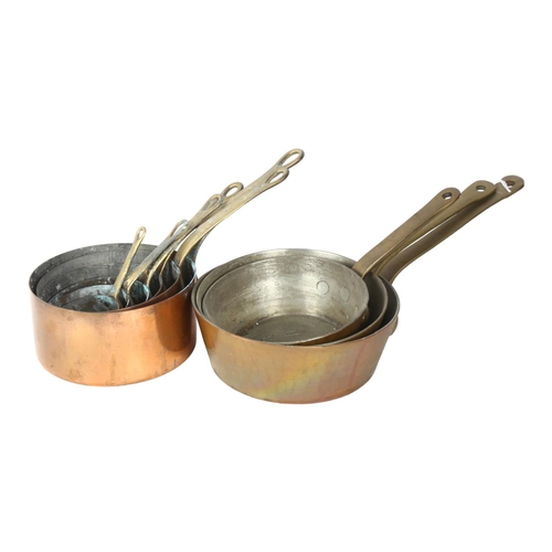 712 - A graduated set of 3 copper pans with brass handles, largest 20cm diameter, and a set of 6 copper pa... 