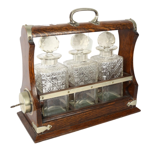 749 - A silver plated oak tantalus, with 3 cut-glass decanters and stoppers, L33.5cm