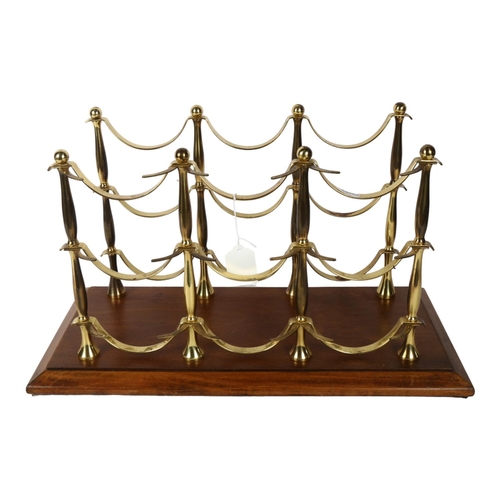 763 - A polished brass 6-bottle wine rack, on wooden plinth