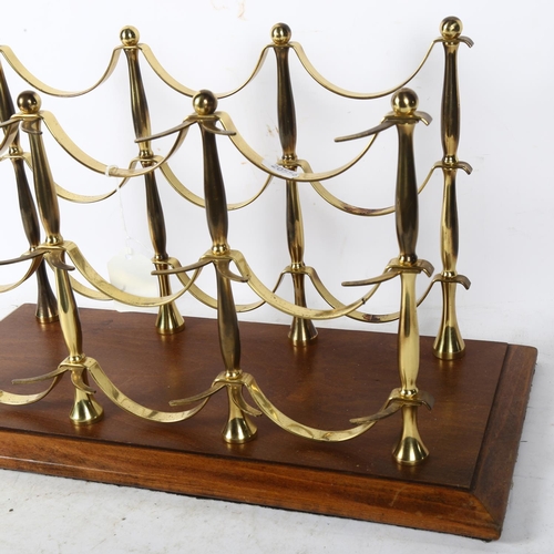 763 - A polished brass 6-bottle wine rack, on wooden plinth