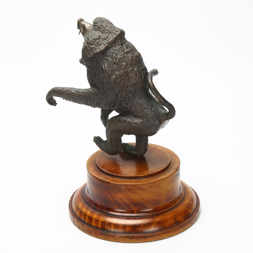 4 - A cast bronze sculpture of a baboon on turned wooden plinth, height 17cm