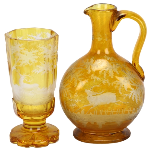 66 - A Bohemian amber flashed glass stag drinking set, comprising moon flask ewer and goblet, goblet heig... 