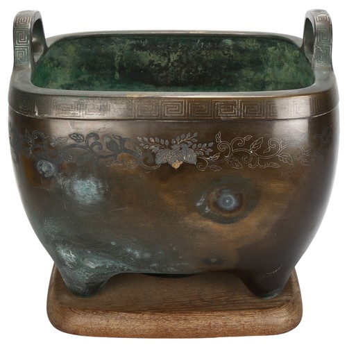 265 - A large Chinese bronze planter, with engraved decoration and silver inlay Greek key border, on woode... 