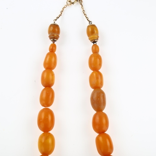 1156 - A graduated single-strand butterscotch amber bead necklace, with 9ct rose gold clasp, bead lengths r... 