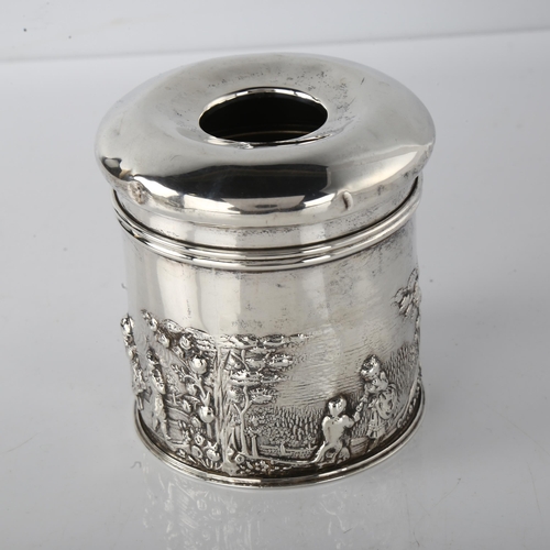 1596 - An Edwardian silver dressing table hair tidy box, cylindrical form with relief embossed country land... 