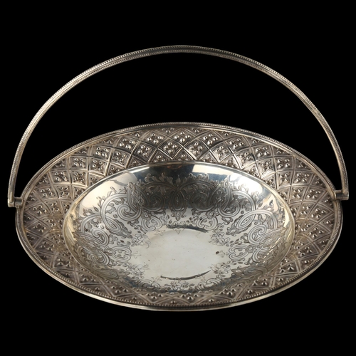 1603 - A large Victorian silver swing-handled bread basket, with engraved and relief embossed decoration, w... 