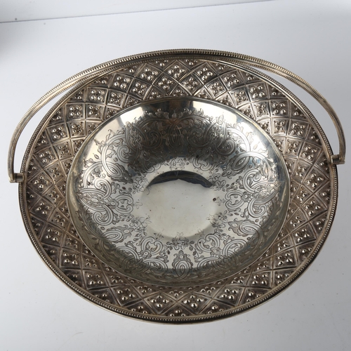 1603 - A large Victorian silver swing-handled bread basket, with engraved and relief embossed decoration, w... 