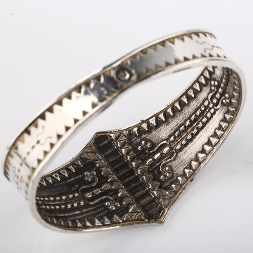 1416 - A Scandinavian Viking Revival bangle, unmarked silver settings with relief embossed decoration, sett... 