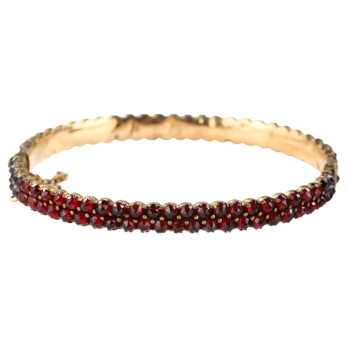 1350 - A Victorian double-row garnet hinged bangle, unmarked yellow metal closed-back settings with faceted... 