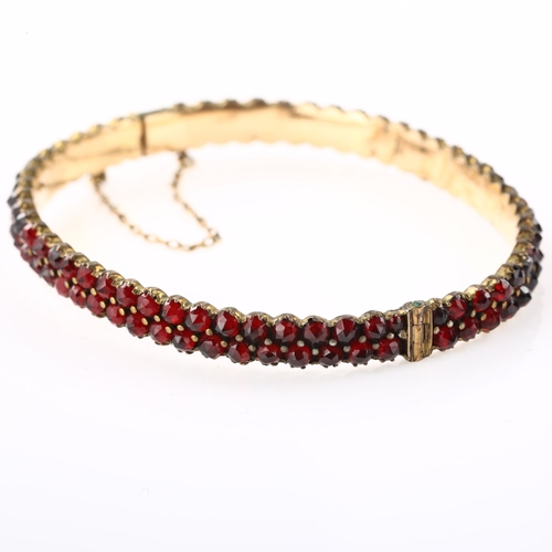 1350 - A Victorian double-row garnet hinged bangle, unmarked yellow metal closed-back settings with faceted... 