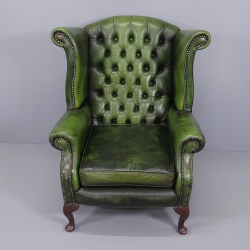 2007 - A Green leather upholstered buttoned wing back fireside armchair and a matched green leather footsto... 