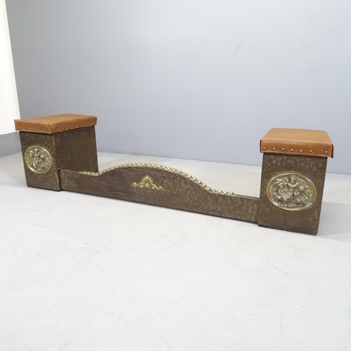 2539 - An antique brass and tooled leather fender stool, with applied cherub design. The seats lift to reve... 